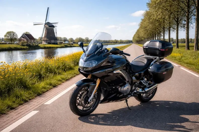 Zwarte toermotor geparkeerd op een Nederlands fietspad met windmolen en bloeiende bloemen op de achtergrond